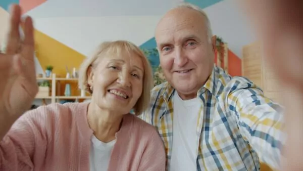 Elderly couple waving hello on a video call